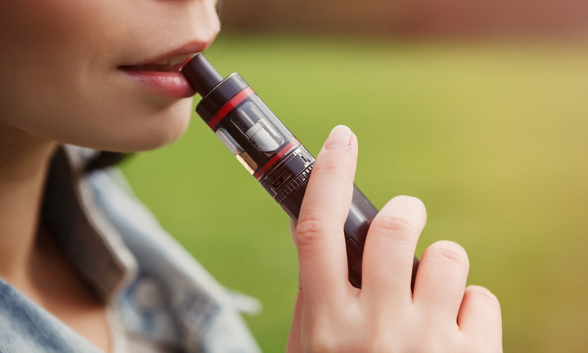 Vaper girl smokes electronic cigarette with tasty flavored glycerin liquid.Young woman holds vaping device with lips.Modern e-cig gadget helps smokers to quit smoking nicotine cigarettes; Shutterstock ID 518659903